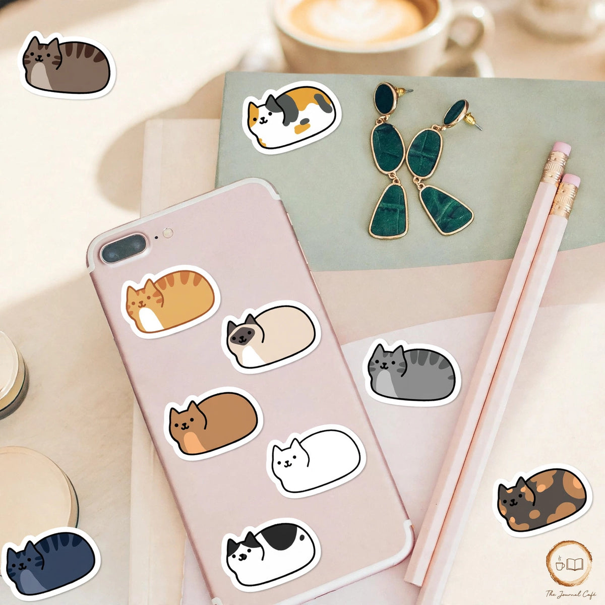 Personality cat stickers — cute loaf cat stickers in many colours styled on a cream café table, The Journal Café