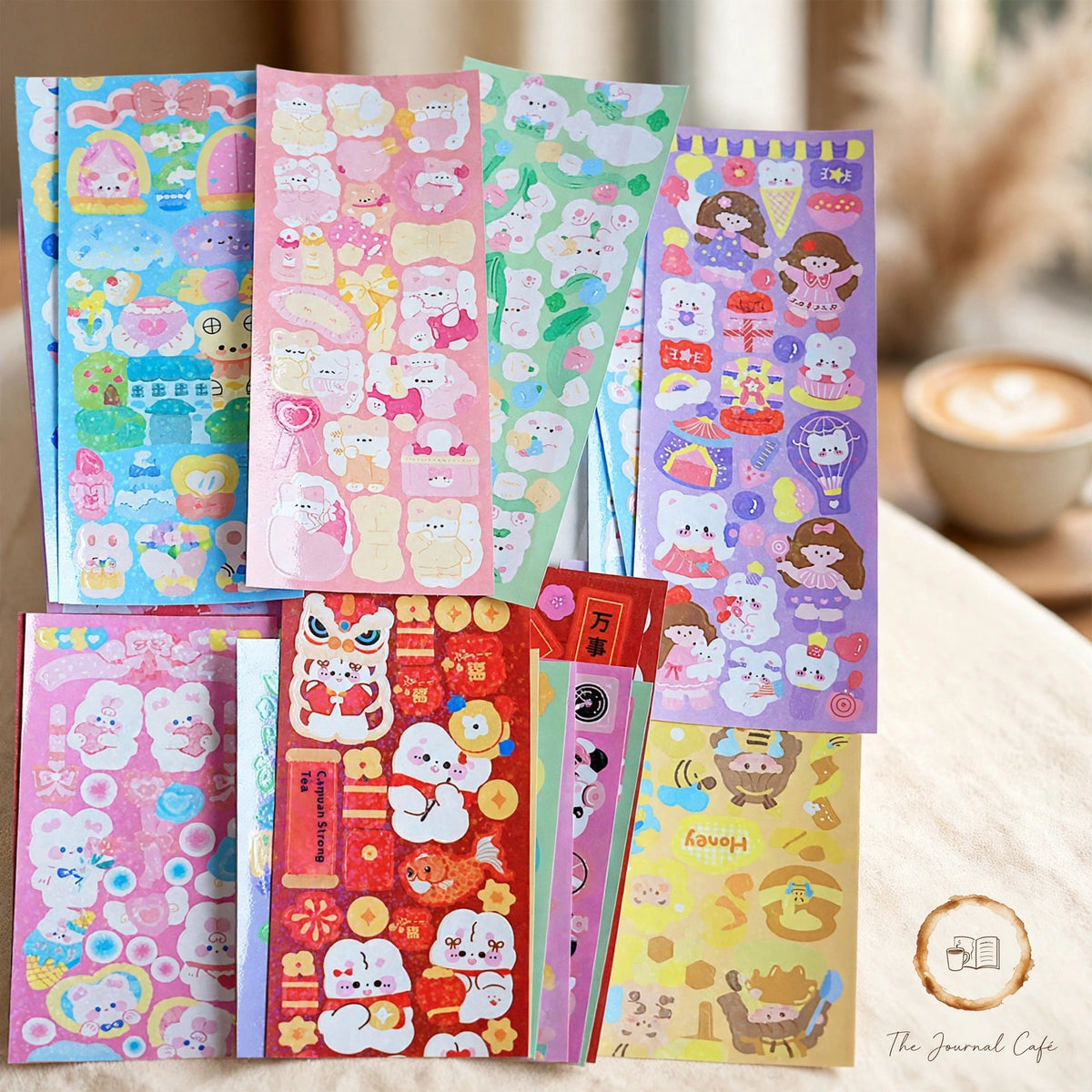 Holographic laser sticker sheets — product photo 2 styled on a cream café table, The Journal Café