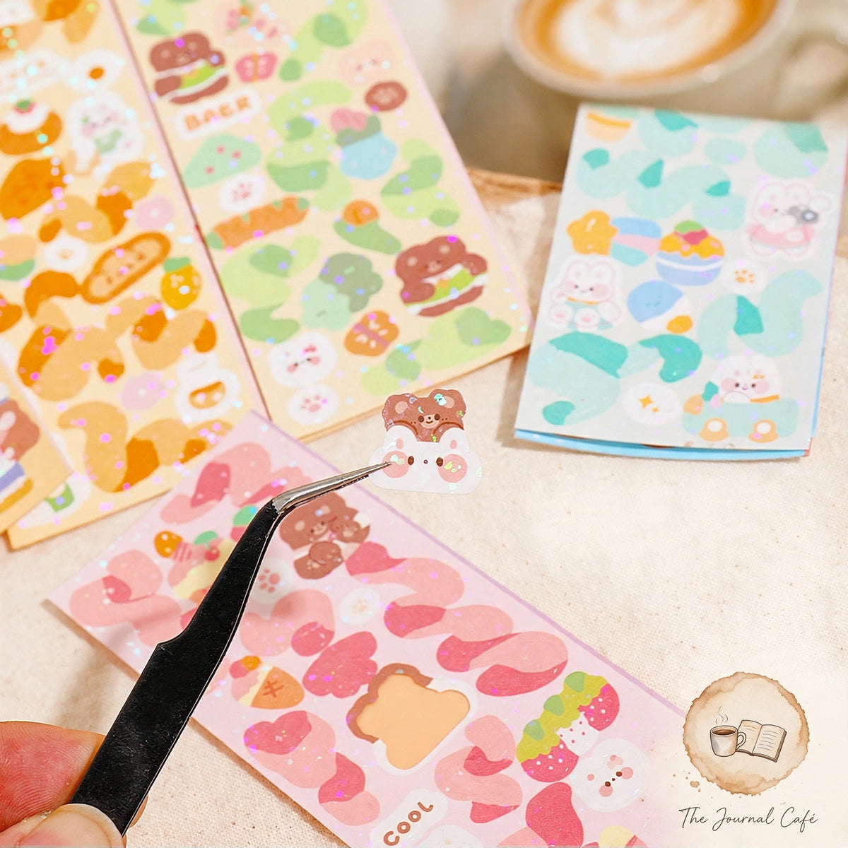 Holographic laser sticker sheets — product photo 5 styled on a cream café table, The Journal Café