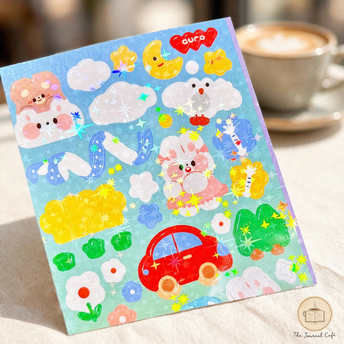 Holographic laser sticker sheets — product photo 6 styled on a cream café table, The Journal Café