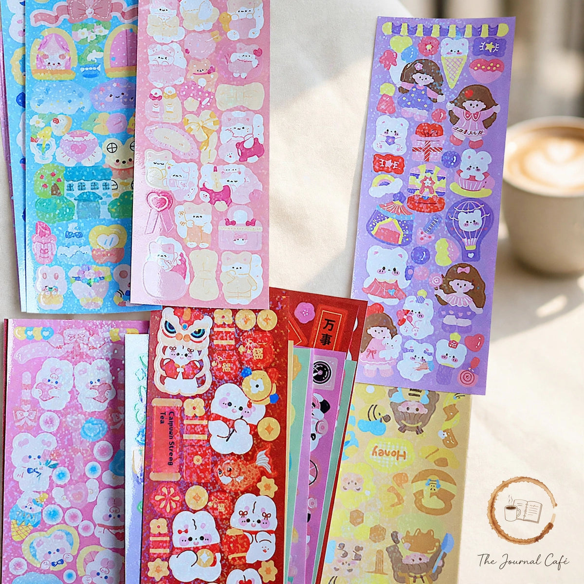 Holographic laser sticker sheets — product photo 7 styled on a cream café table, The Journal Café
